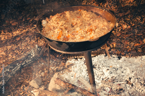 Cast iron pot outdoors, cooking on a fire.