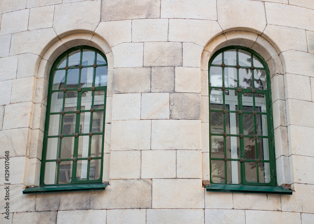 Two historic green window on the yellow wall