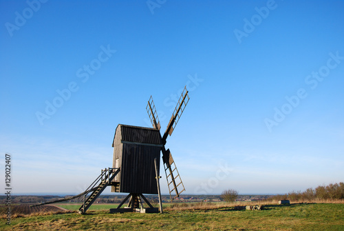Sunlit wooden windmill on a hill