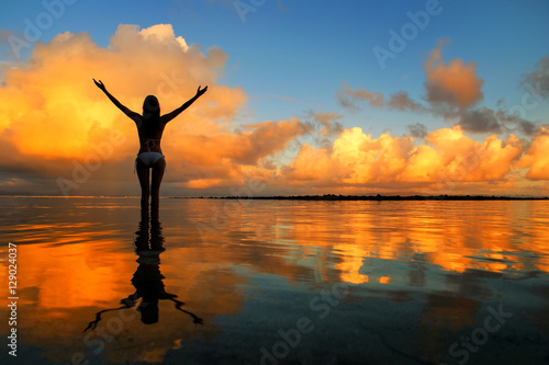 Silhouetted woman standing in a water at sunset on Taveuni Islan photo