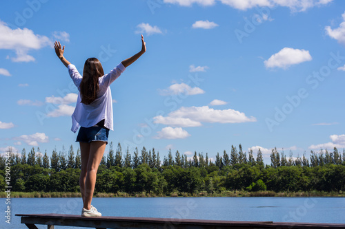 Happy woman with her arms outstretched enjoying on the bench by the pool.