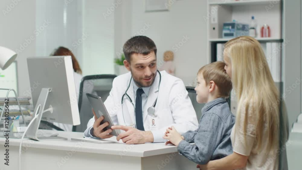 Male Doctor Consults Young Boy and His Mother with a Help of a Tablet. Shot on RED Cinema Camera in 4K (UHD). Male Doctor Consults Young Boy and His Mother with a Help of a Tablet. Shot on RED Cinema Camera in 4K (UHD).