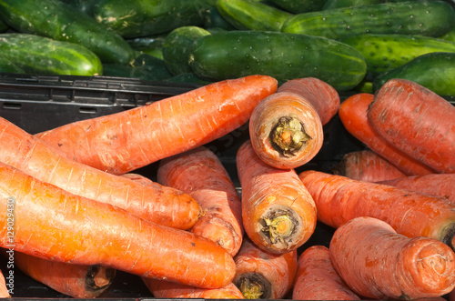 Organic carrots and cucumbers at an outdoor farmers market