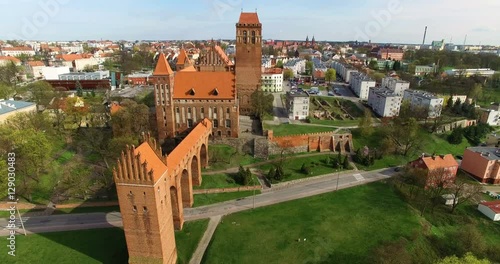 Aerial 4K Scenic view on the longest brick dansker (medieval toilet facility) in Europe and Medieval Teutonic Knight's brick castle in Kwidzyn, with town panorama and cars passing by photo