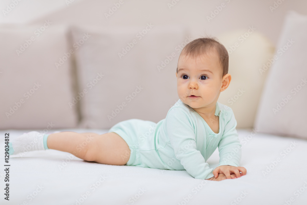 Baby girl on white bed / Cute baby girl lying on her tummy