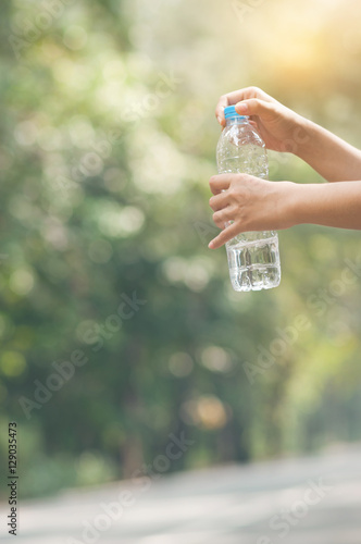 Close up Asian woman hand holding bottle of water on nature back