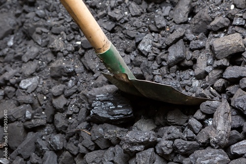 Black coal and shovel lying on a pile in house basement