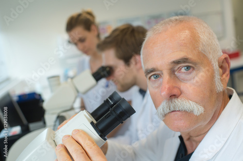 scientist in lab looking through microscope lens