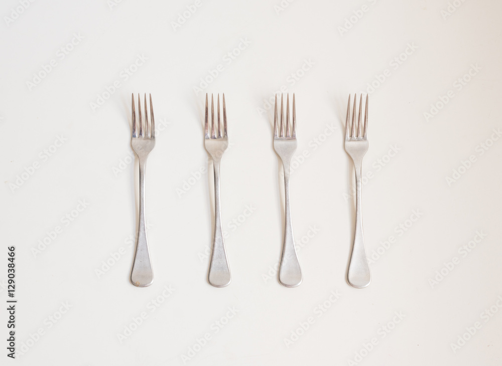 Food background - high angle view of four forks in a row on a white table Food background - high angle view of four forks in a row on a white table