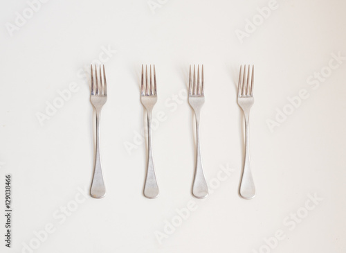 Food background - high angle view of four forks in a row on a white table