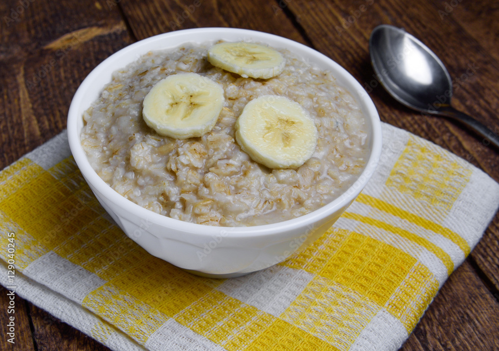 oatmeal in a beautiful white bowl on a warm wooden background with slices of bananas oatmeal in a beautiful white bowl on a warm wooden background with slices of bananas