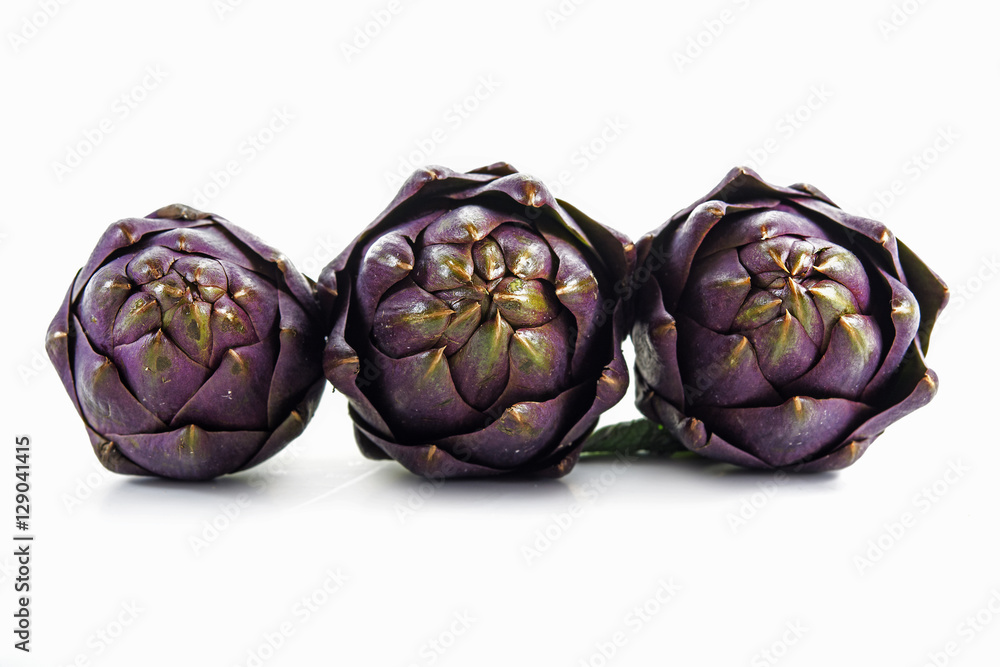 Fototapeta premium three purple artichokes from italy in a row, front shot, isolated on white