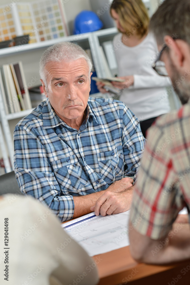 Man in meeting with couple, bemused facial expression Man in meeting with couple, bemused facial expression