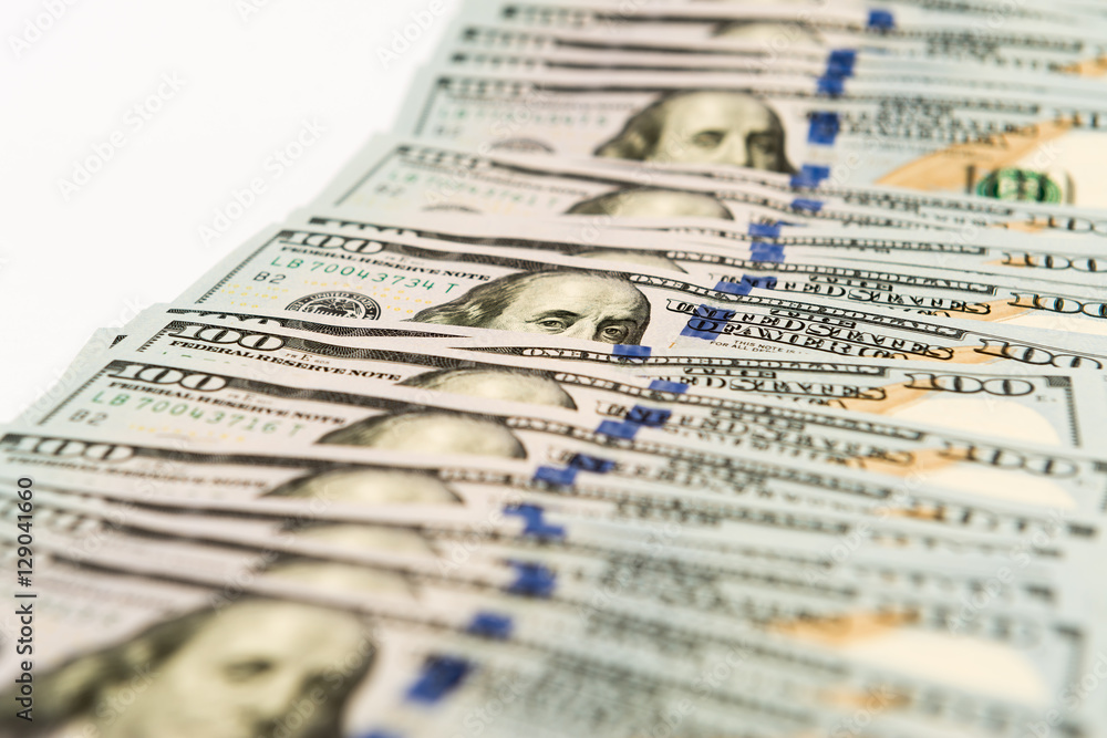 Many hundred dollar banknotes spread on white surface Many hundred dollar banknotes spread on white surface