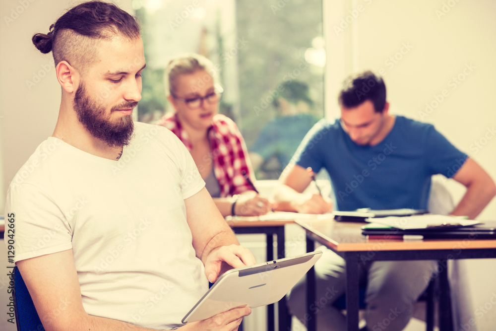 Fototapeta premium Male student with tablet in front of her classmates