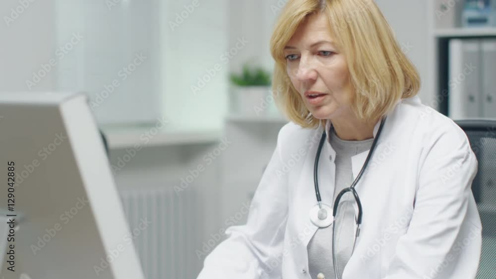 In the Doctor's Office. Mid Adult Female Doctor Works at Her Desktop