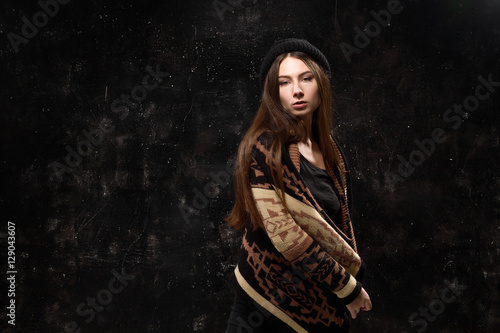 Pretty girl in fashionable clothes on a black background textured wall