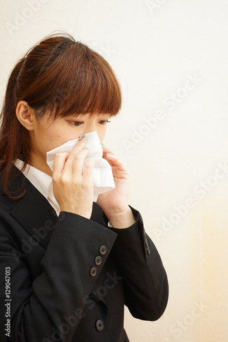 Young woman blowing her nose with tissues