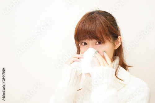 Young woman blowing her nose with tissues