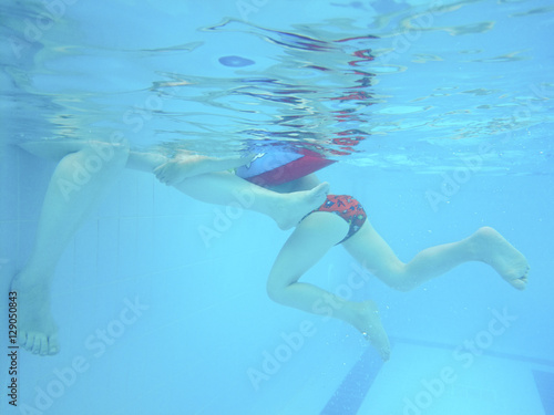 The child's foot and adult under water in the pool.