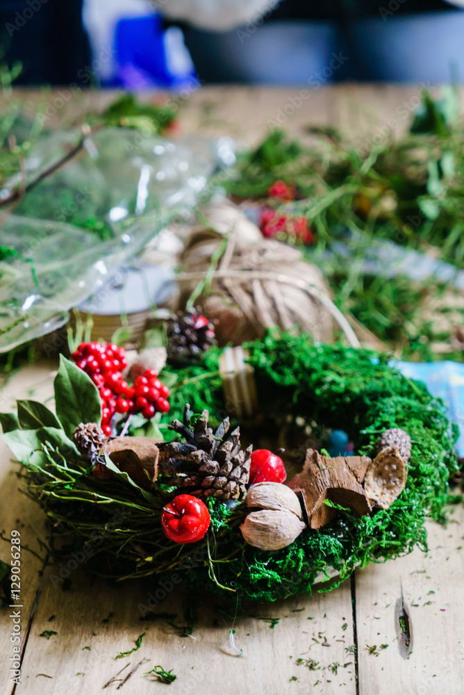 women make traditional christmas door wreath with moss and berry