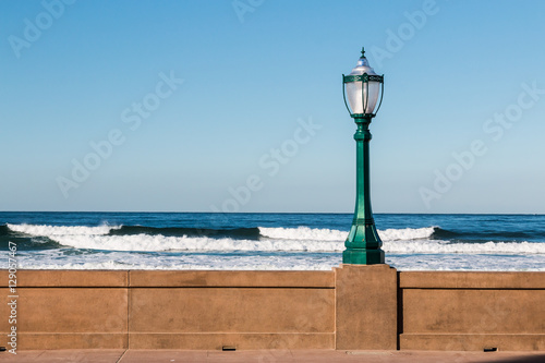 Lamppost on the Mission Beach boardwalk in San Diego, California with ocean waves in the background. © sherryvsmith