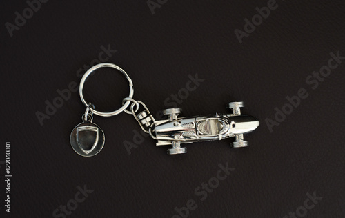 Фотография Silver-chrome keychain with an  old super fast model on leather background