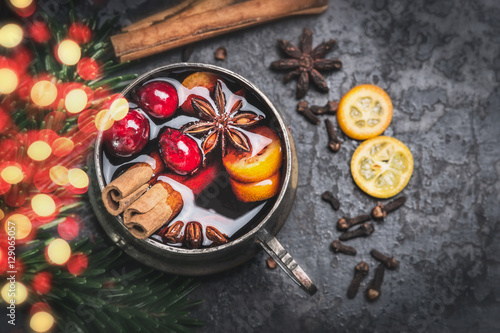 Vintage aged Cup of mulled wine with spices and bokeh lighting on dark vintage background, top view, close up