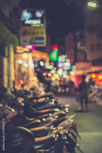 Blurred image of a lane parked with motorcycles in city at night.