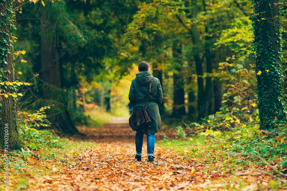 Woman with shoulder bag walking on path in autumn forest. Woman with shoulder bag walking on path in autumn forest.