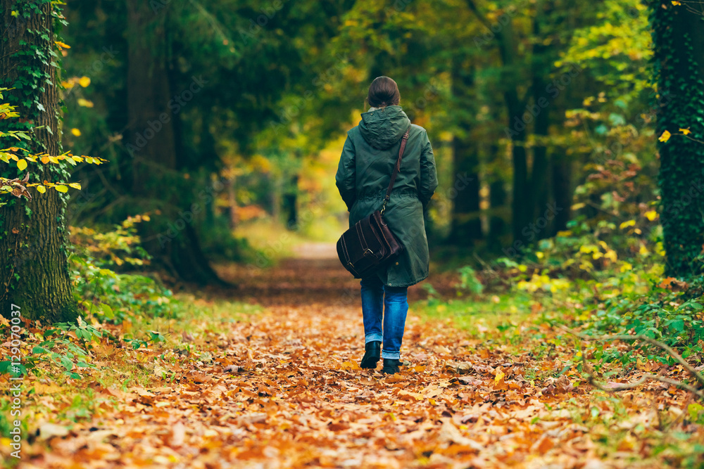 Woman with shoulder bag walking on path in autumn forest. Woman with shoulder bag walking on path in autumn forest.