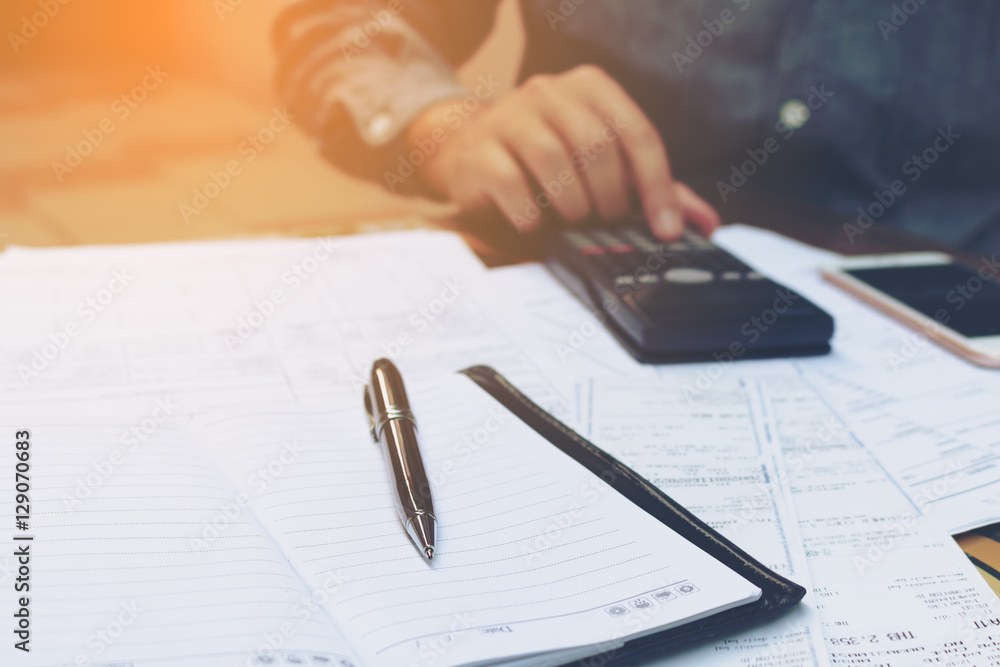 Man using calculator and smartphone on desk in home office. Man using calculator and smartphone on desk in home office.