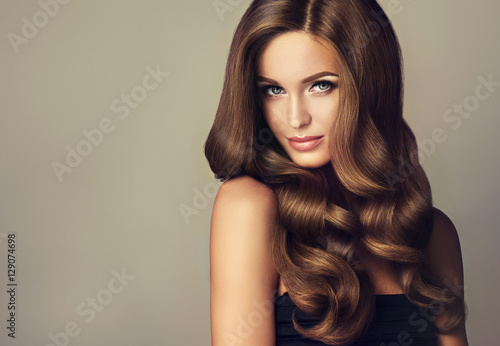 Beautiful model girl with long wavy and shiny hair . Brunette woman with curl...