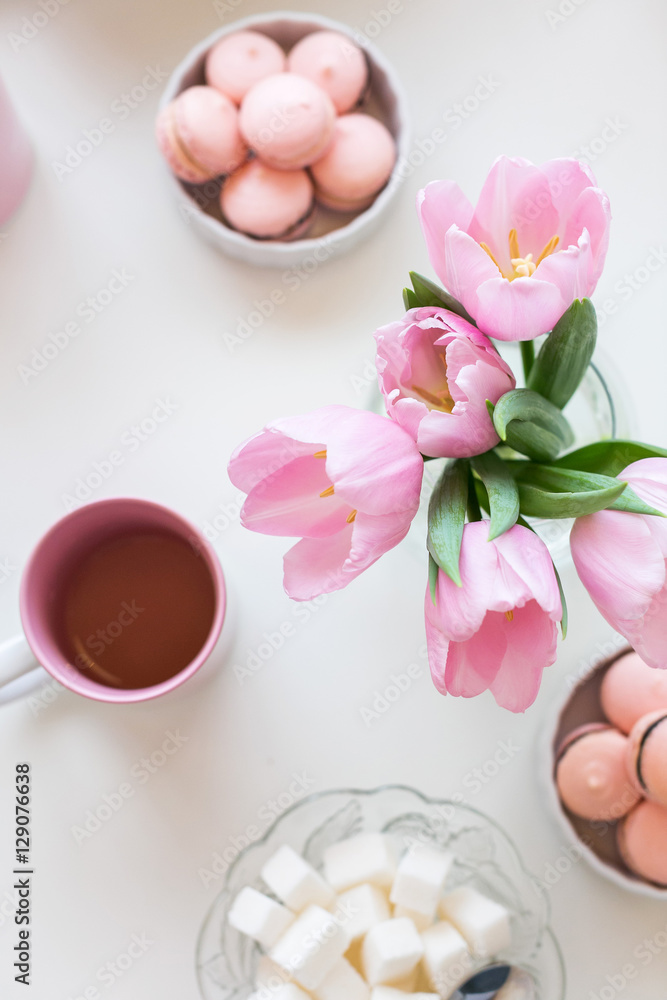 Spring background. Sweets and tea on a table with pink tulips. Still life with fresh bouquet of tulips. Beautifully decorated tray with a bouquet of tulips and a Cup of tea.