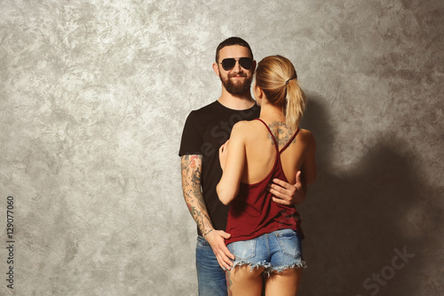 Portrait of young tattooed couple on gray wall background © Africa Studio