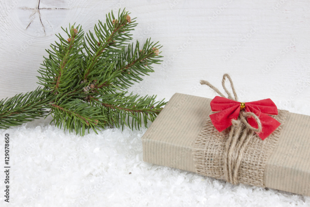 Christmas gift on snow on white wood background