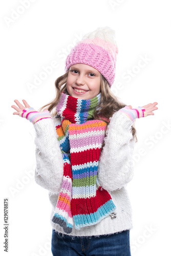 Smiling cute little girl wearing knitted sweater and colorful scarf, hat, mittens isolated on white background. Winter clothes.