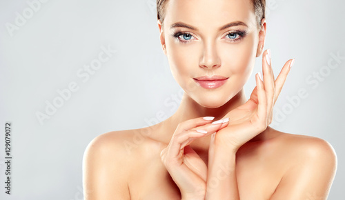 Fotografia Beautiful Young Woman with Clean Fresh Skin touch own face