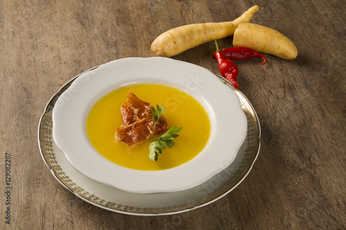 Pumpkin Soup with proschiuto on table photo