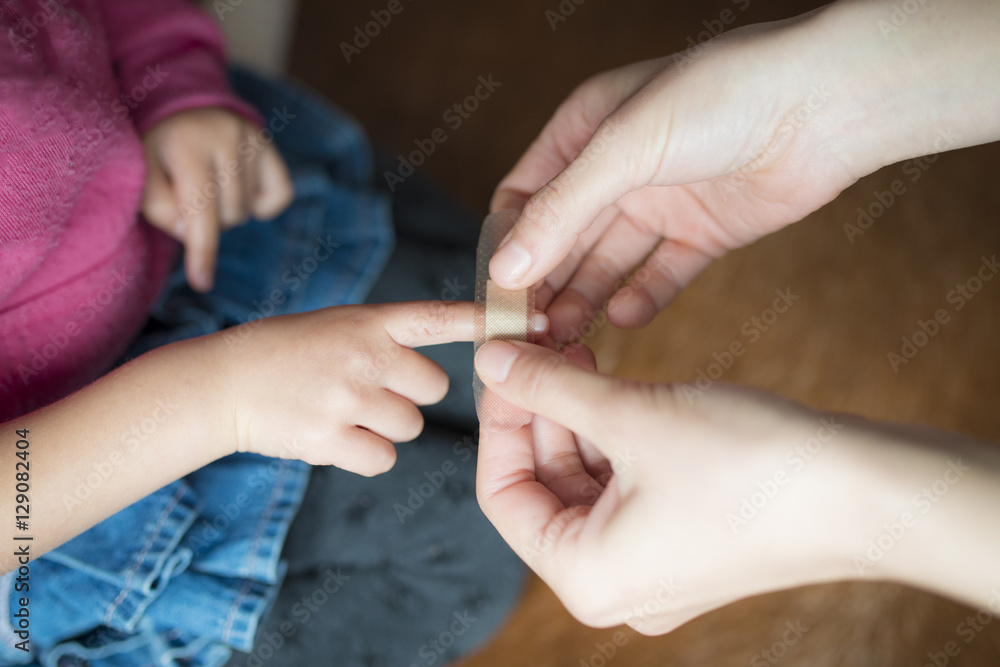 子供の指先に絆創膏を貼る母の手
