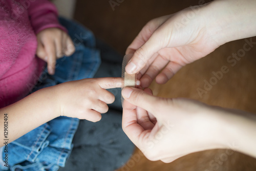 子供の指先に絆創膏を貼る母の手