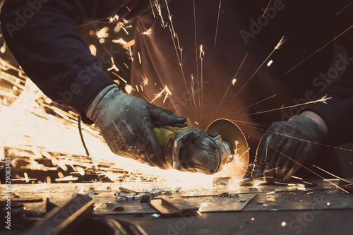 Man sawing metal with a rotary angle grinder on an aluminium surface and generating sparks