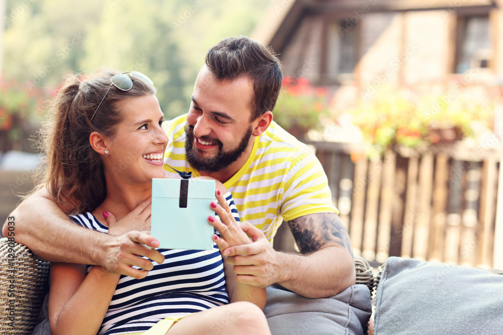 Fototapeta premium Happy couple with present sitting outside