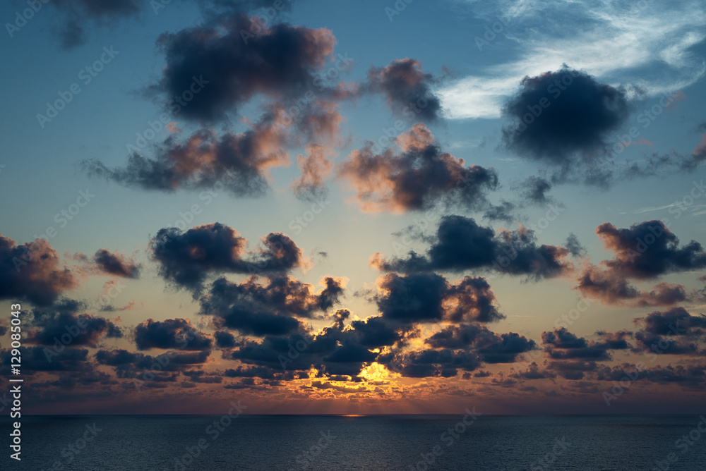 Cloudy sky with sunray onto the ocean at sunset time