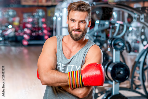 Portrait of muscular boxer with red boxing gloves in the gym
