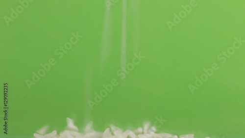 Falling grains of rice on a pile of rice on a green screen.