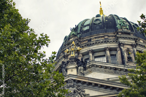 Close up view of histrorical, golden crosss sign on top of Berliner Dom. Majestic 1800s cathedral with an organ with 7,000 pipes, plus royal tombs & a dome for city views. photo