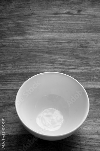 A simple picture of an empty bowl plate on a rustic wooden table bathed in natural light. Uncluttered. Space to the side of the vessel for text (if required).
