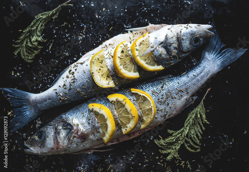 Photography Sea bass fish with lemon on blackboard. Preparing for grill