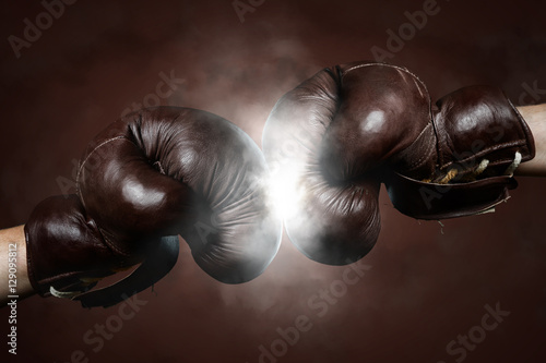 Two old brown boxing gloves hit together